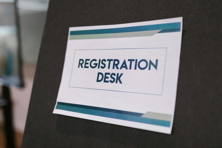 A close-up of a registration desk sign on a dark background.